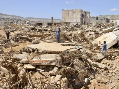 People look for survivors in Derna, Libya, Wednesday, Sept.13, 2023. Search teams are combing streets, wrecked buildings, and even the sea to look for bodies in Derna, where the collapse of two dams unleashed a massive flash flood that killed thousands of people. (AP Photo/Yousef Murad)