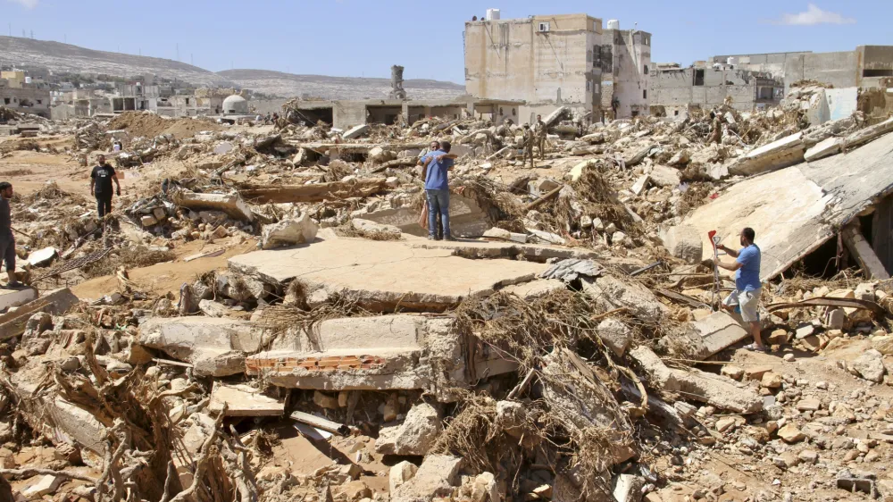 People look for survivors in Derna, Libya, Wednesday, Sept.13, 2023. Search teams are combing streets, wrecked buildings, and even the sea to look for bodies in Derna, where the collapse of two dams unleashed a massive flash flood that killed thousands of people. (AP Photo/Yousef Murad)