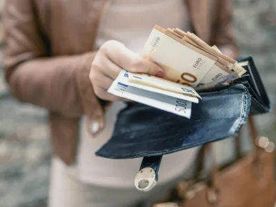 Woman holding in hands wallet with euro money. City girl is taking out money from wallet