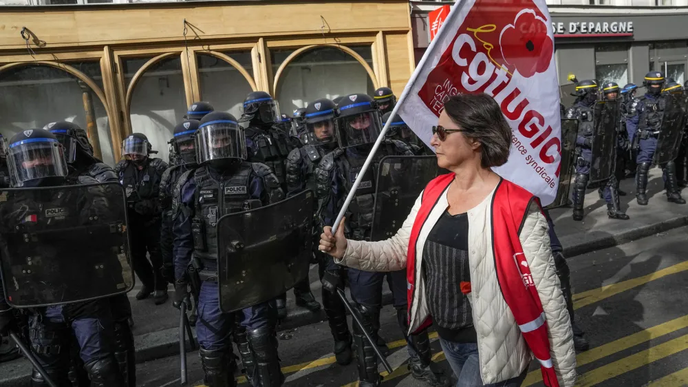 A demonstrator walks past police officers with a union flag during a protest against police violence, Saturday, Sept. 23, 2023. Families, community groups and far-left activists marched in cities around France on Saturday to decry racism and police brutality, putting authorities on edge at a time when French police are deployed en masse for a string of high-security events. (AP Photo/Michel Euler)
