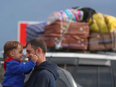 A refugee from Nagorno-Karabakh region holds a child while standing next to a car upon their arrival in the border village of Kornidzor, Armenia, September 26, 2023. REUTERS/Irakli Gedenidze   TPX IMAGES OF THE DAY