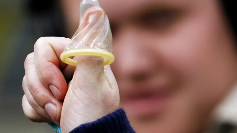 A member of the No To Pope Coalition displays a condom on her thumb during a media call in Sydney in this July 4, 2008 file photo. Using condoms may sometimes be justified to stop the spread of AIDS, Pope Benedict says in a new book, in surprise comments that relax one of the Vatican's most controversial positions. REUTERS/Daniel Munoz/Files (AUSTRALIA - Tags: RELIGION SOCIETY)