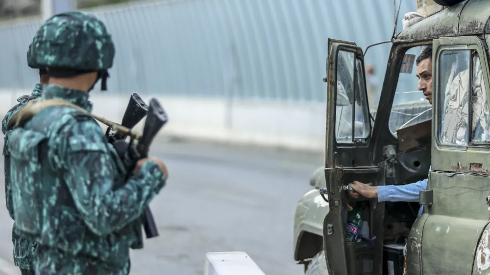 Sergey Astsetryan, an ethnic Armenian resident of Nagorno-Karabakh, right, says goodbye to Azerbaijani border guard servicemen after they checked his Soviet-made vehicle at the Lachin checkpoint on the way from Nagorno-Karabakh to Armenia, in Azerbaijan, Sunday, Oct. 1, 2023. Astsetrayn was one of the last residents of Nagorno-Karabakh to drive out of the region in his own vehicle as part of a grueling weeklong exodus of over 100,000 people — more than 80% of the residents — after Azerbaijan reclaimed the area in a lightning military operation. (AP Photo/Aziz Karimov)