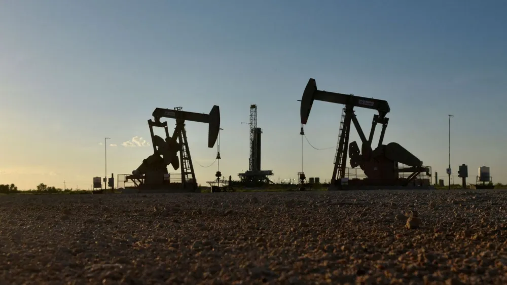 FILE PHOTO: FILE PHOTO: Pump jacks operate in front of a drilling rig in an oil field in Midland, Texas U.S. August 22, 2018. REUTERS/Nick Oxford/File Photo