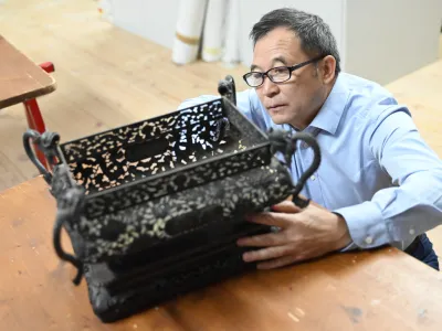 Kustos Guo Fuxiang si ogleduje enega od predmetov, ki jih je Skušek pred sto leti v Slovenijo pripeljal iz Kitajske.