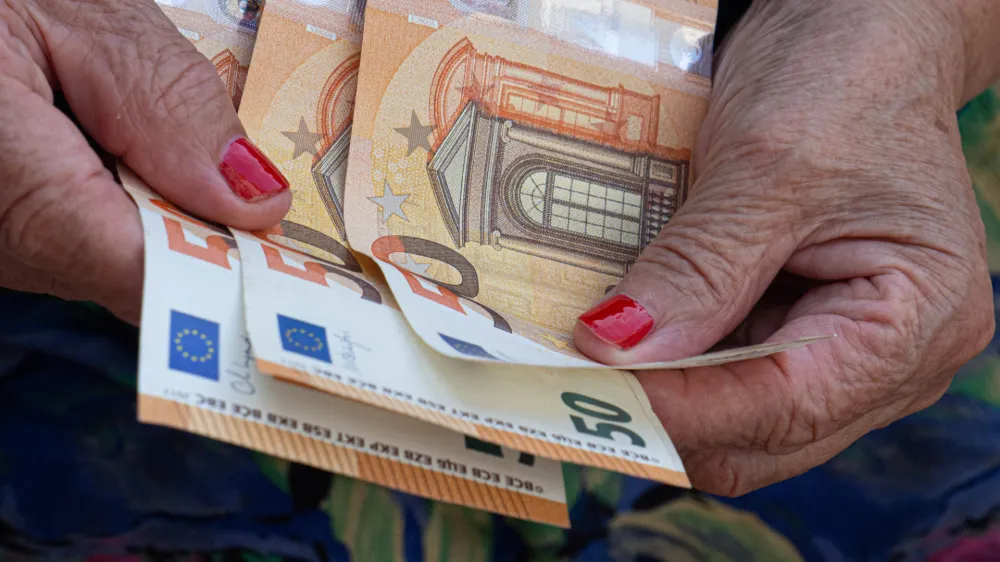 Woman's hands are holding a few euro coins. Pension, poverty, social problems and the theme of old age. Saving.