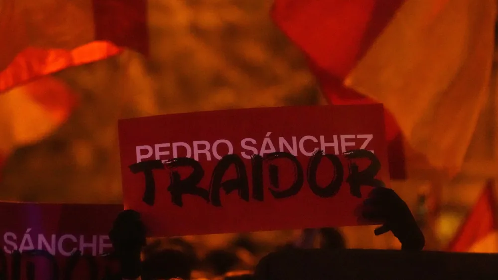 A sign reading 'Pedro Sanchez, Traitor' is held up during a protest by right wing demonstrators near the national headquarters of Spain's Socialist Party in Madrid, Spain, Tuesday, Nov. 7, 2023. The Spanish capital saw its second night in a row of clashes between police and protesters who oppose negotiations between Spain's acting government and Catalan separatist parties over a possible amnesty for thousands involved in Catalonia's independence movement. (AP Photo/Paul White)