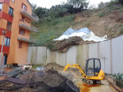 Delavci odstranjujejo približno 25 metrov dolgo plazino in utrjujejo brežino ob bloku. 