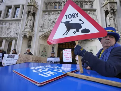 Protesters stand outside the Supreme Court in London, Wednesday, Nov. 15, 2023. Britain's Supreme Court has ruled that the government's contentious plan to send some migrants on a one-way trip to Rwanda is illegal. (AP Photo/Kirsty Wigglesworth)