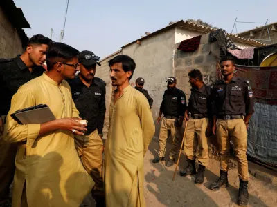 A worker from the National Database and Registration Authority (NADRA), along with police officers, speaks to an Afghan citizen while checking identity cards, during a door-to-door search and verification drive for undocumented Afghan nationals, in an Afghan Camp on the outskirts of Karachi, Pakistan, November 21, 2023. REUTERS/Akhtar Soomro