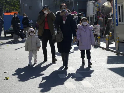 Residents wearing masks pass by a children's hospital in Beijing, Friday, Nov. 24, 2023. Chinese officials say they did not detect any "unusual or novel diseases" in the country, the World Health Organization said Thursday, following an official request by the U.N. health agency for information about a potentially worrying spike in respiratory illnesses and clusters of pneumonia in children. (AP Photo/Ng Han Guan)