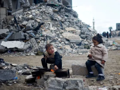 Palestinian children sit by the fire next to the rubble of a house hit in an Israeli strike during the conflict, amid a temporary truce between Hamas and Israel, in Khan Younis in the southern Gaza Strip November 27, 2023. REUTERS/Mohammed Salem