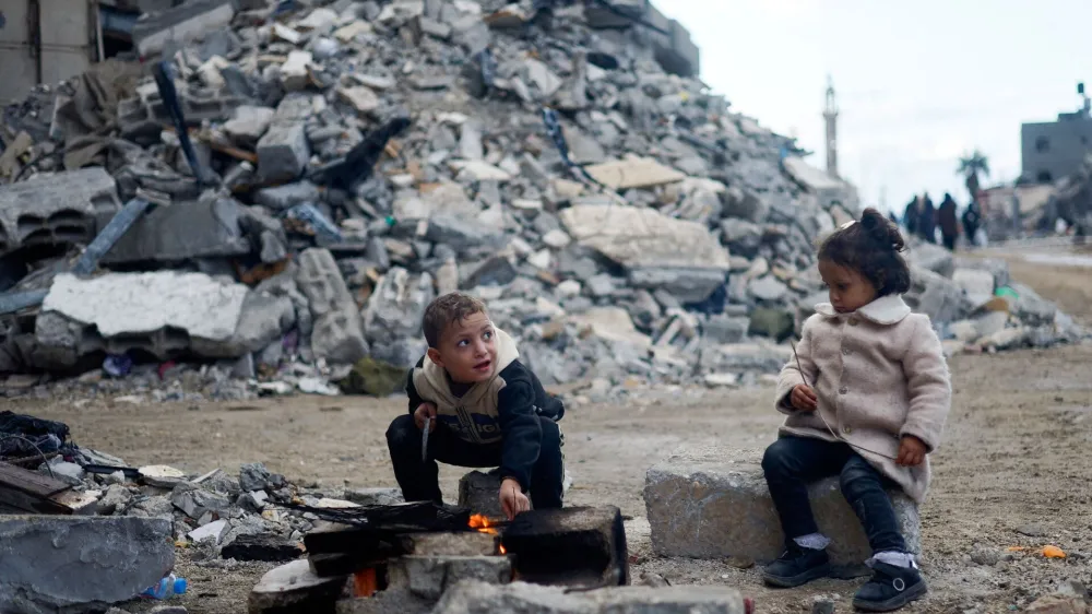 Palestinian children sit by the fire next to the rubble of a house hit in an Israeli strike during the conflict, amid a temporary truce between Hamas and Israel, in Khan Younis in the southern Gaza Strip November 27, 2023. REUTERS/Mohammed Salem