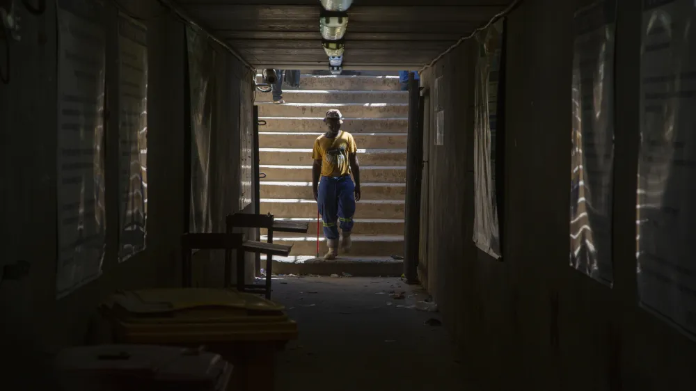 A miner walks at the entrance of a goldmine shaft in Springs, South Africa, Tuesday, Oct. 24, 2023. A group of miners from an unregistered, rival union are holding around 500 of their colleagues underground for the second day at the mine over a union dispute. Some 15 miners have been injured in scuffles, the head of the mine said on Tuesday. (AP Photo/Denis Farrell)