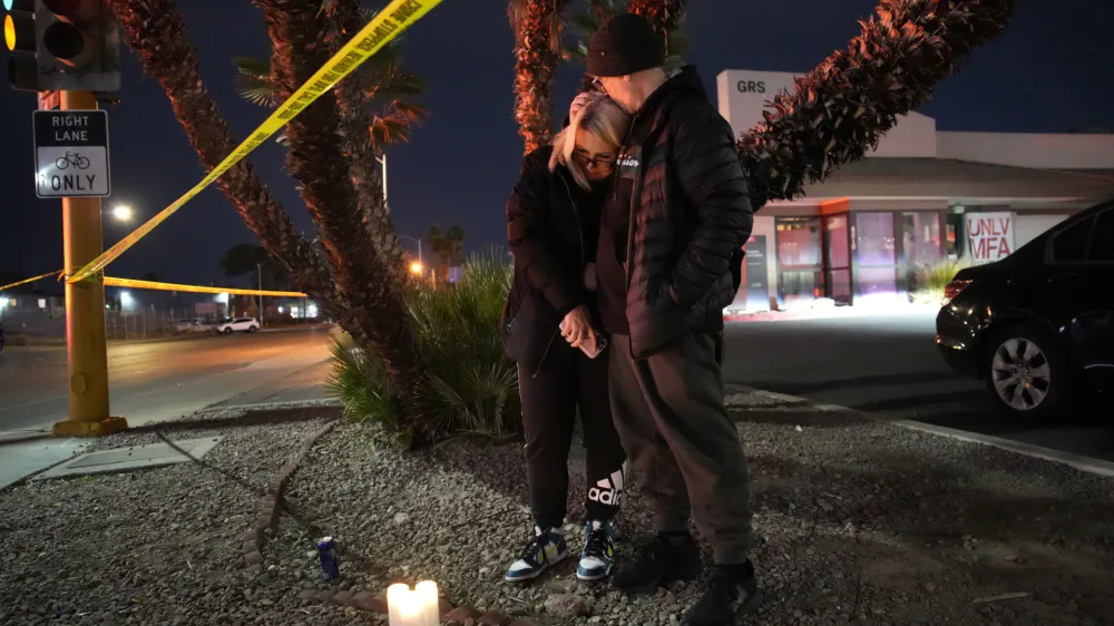 Sean Hathcock, right, kisses Michelle Ashley after the two left candles for victims of a shooting at the University of Nevada, Las Vegas, Wednesday, Dec. 6, 2023, in Las Vegas. The two graduated from the school and live nearby. (AP Photo/John Locher)