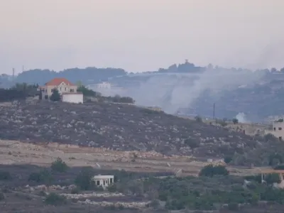 A screenshot from video footage provided to Reuters by Rai that was shot from the Lebanon side of the Israel-Lebanon border, October 13, 2023. The large plumes of smoke rising behind the hill to the right of the orange-roofed building indicate the location, close to the Lebanese village of Alma al-Chaab, that was hit by the first of two rounds fired by an Israeli tank, killing Reuters visuals journalist Issam Abdallah and wounding six other reporters. To match Special Report ISRAEL-LEBANON/JOURNALIST  Rai/Handout via REUTERS  THIS IMAGE HAS BEEN SUPPLIED BY A THIRD PARTY. NO RESALES. NO ARCHIVES. MANDATORY CREDIT.