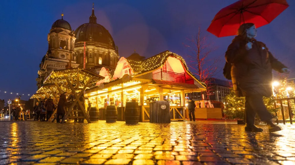 A person strolls past Christmas lights and decorations at the outdoor Christmas market at Humboldt Forum in front of Berlin Cathedral (Berliner Dom) in central Berlin, Germany, December 11, 2023. REUTERS/Lisi Niesner