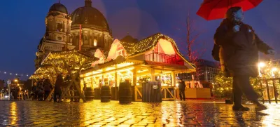 A person strolls past Christmas lights and decorations at the outdoor Christmas market at Humboldt Forum in front of Berlin Cathedral (Berliner Dom) in central Berlin, Germany, December 11, 2023. REUTERS/Lisi Niesner