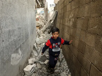 14 December 2023, Palestinian Territories, Rafah: A Palestinian child walks amidst the debris of a destroyed house following Israeli bombardment, amid ongoing battles between Israel and the Palestinian militant group Hamas. Photo: Abed Rahim Khatib/dpa