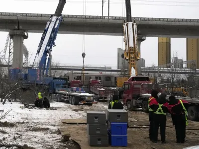 Police officers watch over near the site of train collision on the western district in Beijing, Friday, Dec. 15, 2023. Two subway trains have collided in heavy snow in Beijing, sending over 500 people to the hospital, including more than 100 with broken bones. Authorities said Friday the accident occurred the previous evening in Beijing's mountainous west on an above-ground portion of the sprawling subway system's Changping line. (AP Photo/Ng Han Guan)