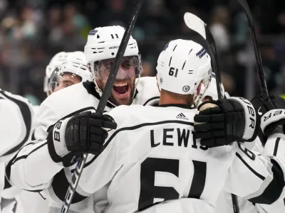 Los Angeles Kings center Anze Kopitar (11) hugs center Trevor Lewis (61) as they celebrate a win against the Seattle Kraken in a shootout in an NHL hockey game Saturday, Dec. 16, 2023, in Seattle. (AP Photo/Lindsey Wasson)