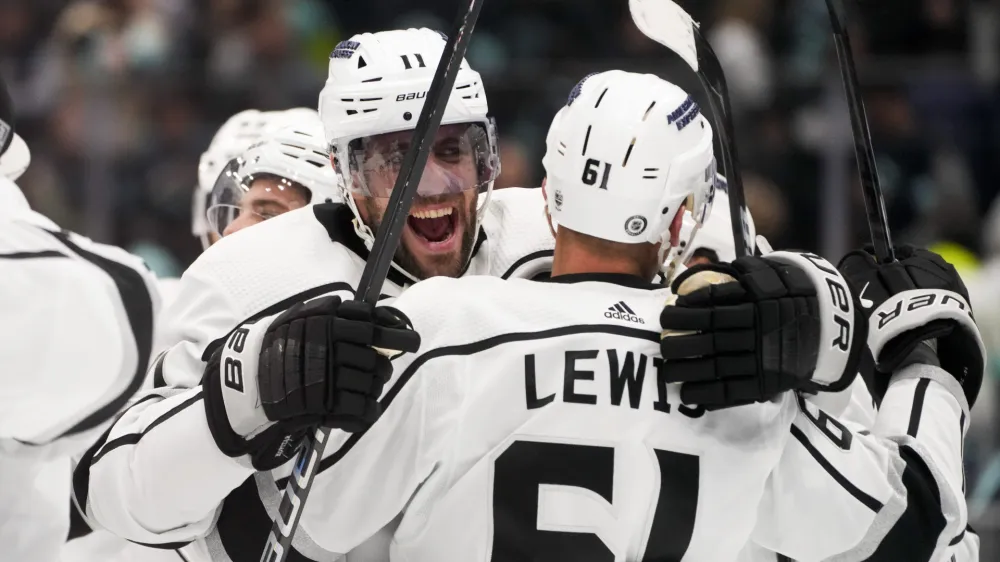 Los Angeles Kings center Anze Kopitar (11) hugs center Trevor Lewis (61) as they celebrate a win against the Seattle Kraken in a shootout in an NHL hockey game Saturday, Dec. 16, 2023, in Seattle. (AP Photo/Lindsey Wasson)