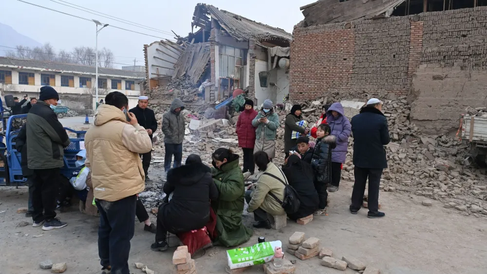 Residents keep warm by a fire next to damaged buildings at Dahejia town following the earthquake in Jishishan county, Gansu province, China December 19, 2023. cnsphoto via REUTERS  ATTENTION EDITORS - THIS IMAGE WAS PROVIDED BY A THIRD PARTY. CHINA OUT. NO COMMERCIAL OR EDITORIAL SALES IN CHINA