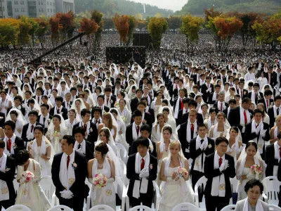 Couples from around the world participate in a mass wedding ceremony arranged by the Rev. Sun Myung Moon's Unification Church at Sun Moon University in Asan, south of Seoul, South Korea, Wednesday, Oct. 14, 2009. The brides wore wedding dresses or their national dress; the men wore black suits with red ties, with white scarves around their necks. (AP Photo/Lee Jin-man)