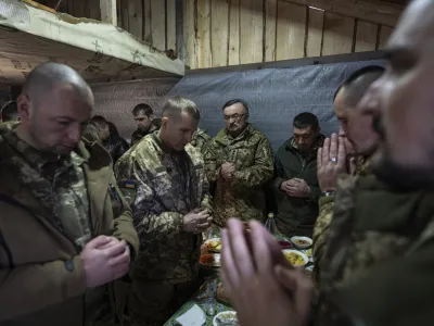 Ukrainian servicemen pray during a funeral dinner of their fallen comrade Vasyl Medviychuk at the Carpathian's mountains in Krasnyk village, Ukraine, Thursday, Dec. 28, 2023. (AP Photo/Evgeniy Maloletka)