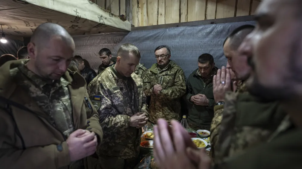 Ukrainian servicemen pray during a funeral dinner of their fallen comrade Vasyl Medviychuk at the Carpathian's mountains in Krasnyk village, Ukraine, Thursday, Dec. 28, 2023. (AP Photo/Evgeniy Maloletka)