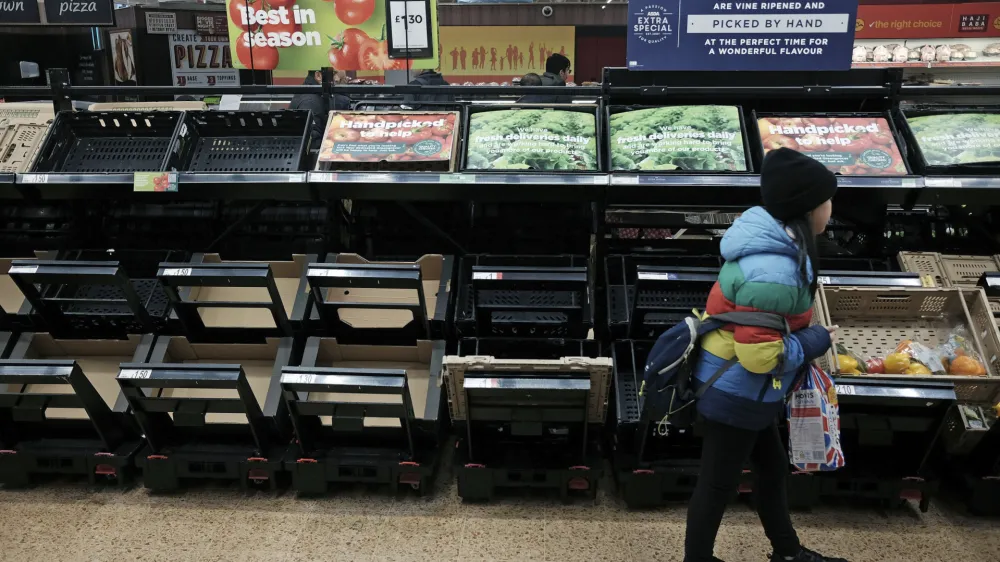 A girl walks by empty fruit and vegetable shelves at an Asda in east London, Saturday, Feb. 25, 2023. British people have had to ration tomatoes and cucumbers for the past two weeks amid a shortage of fresh vegetables. Officials blame the problem on recent bad weather in Spain and North Africa, but with other European countries not suffering the same shortages, some people question if Brexit is to blame. (Yui Mok/PA via AP)