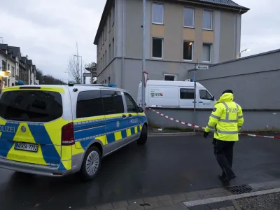 03 January 2024, North Rhine-Westphalia, Finnentrop: A police man stands next to a police vichel near the Lennepark, following the violent death of a 72-year-old man in Finnentrop. A 19-year-old has handed himself in to the police. Photo: Kai Osthoff/dpa
