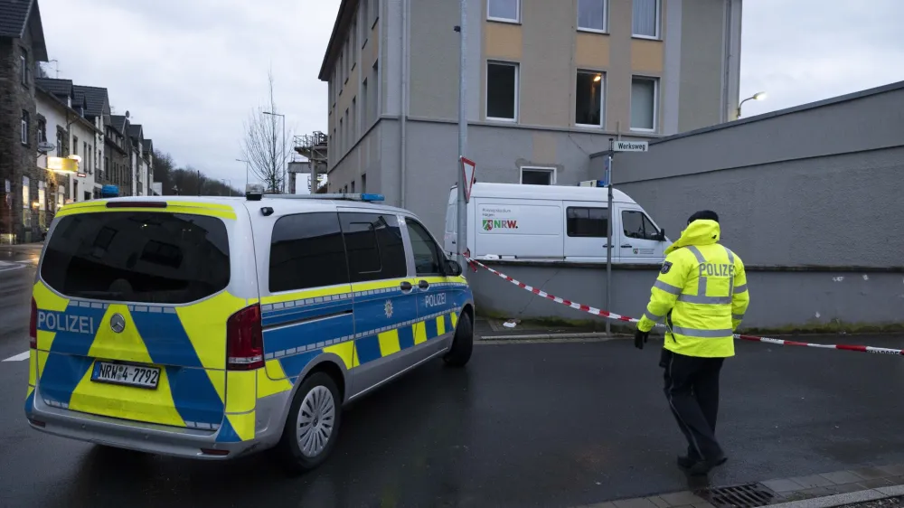 03 January 2024, North Rhine-Westphalia, Finnentrop: A police man stands next to a police vichel near the Lennepark, following the violent death of a 72-year-old man in Finnentrop. A 19-year-old has handed himself in to the police. Photo: Kai Osthoff/dpa