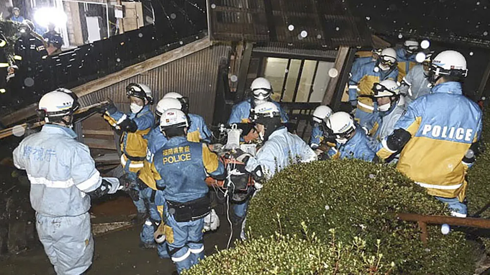 In this photo released by Metropolitan Police Department via Kyodo News, police officers rescue a woman from a collapsed house in Suzu, Ishikawa prefecture, Japan, Saturday, Jan. 6, 2024. The woman in her 90s was pulled alive from the collapsed house late Saturday, 124 hours after a major quake slammed the region, killing scores of people, toppling buildings and setting off landslides. (Metropolitan Police Department/Kyodo News via AP)