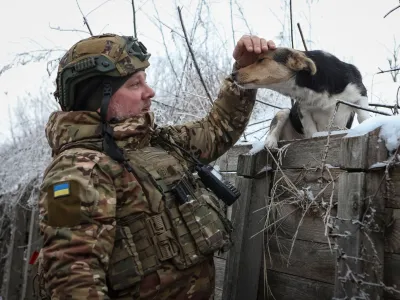 Artem, a serviceman of infantry battalion of the 61st mechanised brigade pets a dog in a trench at a position near the frontline, amid Russia's attack on Ukraine, in Kharkiv region, Ukraine January 6, 2024. REUTERS/Sofiia Gatilova