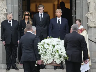 Former President Donald Trump, center right, stands with his wife Melania, second left, their son Barron, center left, and father-in-law Viktor Knavs, as the coffin carrying the remains of Amalija Knavs, the former first lady's mother, is carried into the Church of Bethesda-by-the-Sea for her funeral, in Palm Beach, Fla., Thursday, Jan. 18, 2024. (AP Photo/Rebecca Blackwell)