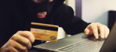 W2M8KX Man in robber mask and hood misappropriates personal bank data. Cyber fraudster attacks online banking system. Hacker makes financial fraud via