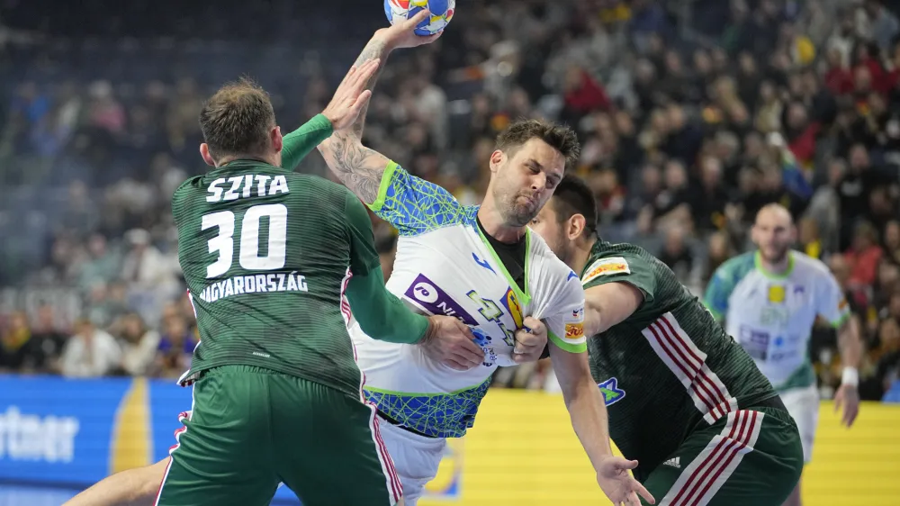 Slovenia's Dean Bombac, center, and Hungary's Zoltan Szita, left, challenge during the Handball European Championship 5th place match between Hungary and Slovenia in Cologne, Germany, Friday, Jan. 26, 2024. (AP Photo/Martin Meissner)