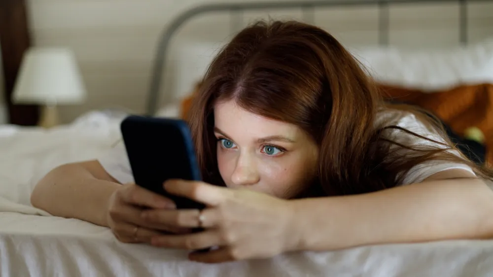 Night chat on smartphone. A young girl surfs the internet in bed, plays games or watches videos. Phone addiction.