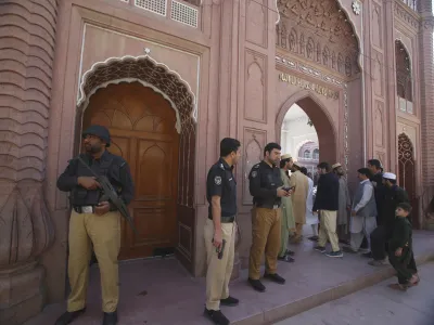 Police officers stand guard as people arrive to attend first Friday prayer during the Muslim's holy fasting month of Ramadan, at the historical Sunehri mosque, in Peshawar, Pakistan, Friday, March 15, 2024. (AP Photo/Muhammad Sajjad)