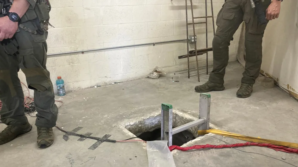 Law enforcement officers stand by the opening of a cross-border tunnel on Monday, May 16, 2022 between Mexico's Tijuana into the San Diego area. Authorities have announced the discovery of the underground smuggling tunnel on Mexico's border, running the length of a football field on U.S. soil to a warehouse in an industrial area. The cross-border tunnel from Tijuana to the San Diego area was built in one of the most fortified stretches of the border, illustrating the limitations of former President Donald Trump's border wall. (AP Photo/Elliot Spagat)