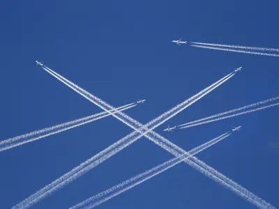 A lot of passenger airplanes on the air, busy air traffic, traveling high season starts concept. White planes against blue sky. Photo manipulation.