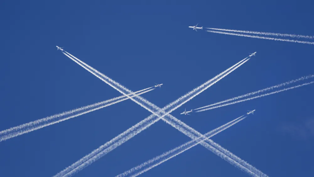 A lot of passenger airplanes on the air, busy air traffic, traveling high season starts concept. White planes against blue sky. Photo manipulation.