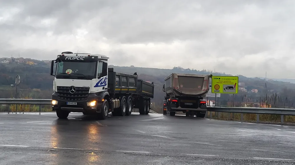 Tovornjaki nenehno odvažajo izkopani material z gradbišč (na fotografiji Dekani).