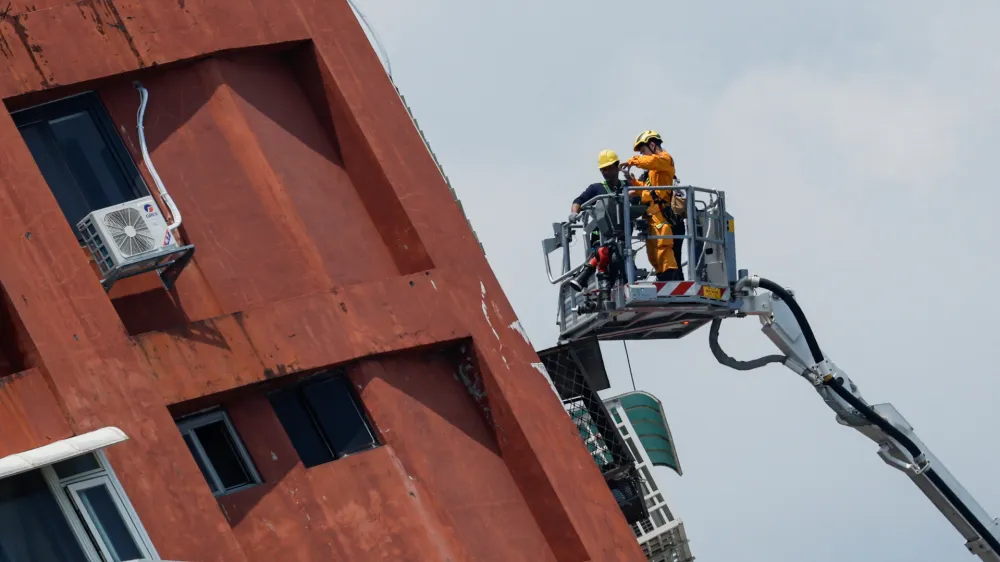Workers carry out operations while on an elevated platform of a firefighting truck at the site where a building collapsed, following the earthquake, in Hualien, Taiwan April 4, 2024. REUTERS/Carlos Garcia Rawlins