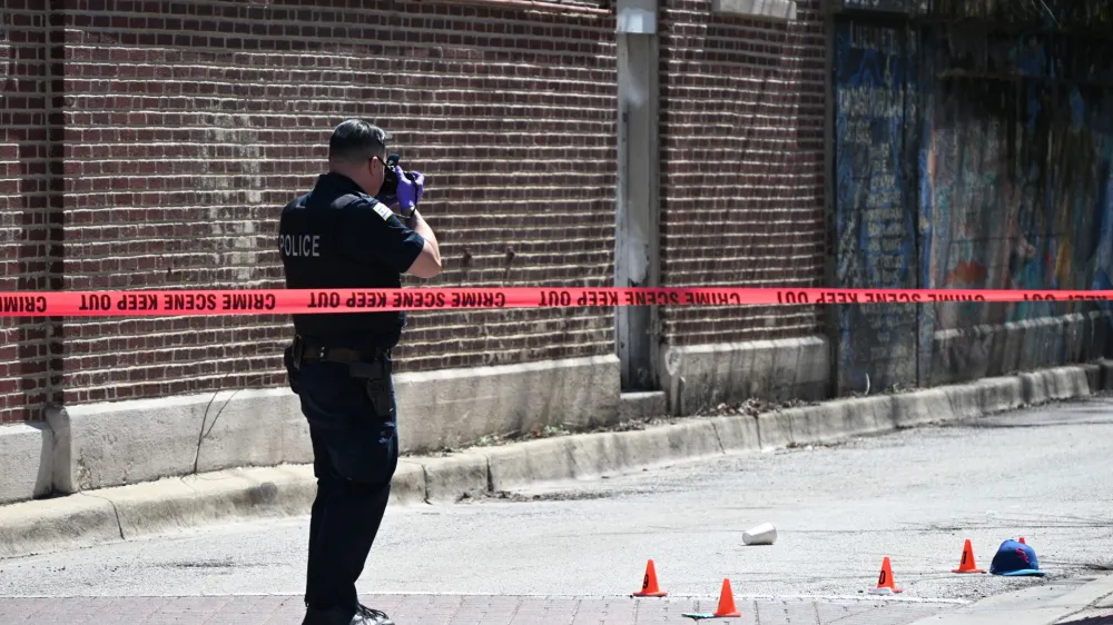 09 April 2024, US, Chicago: A Police officer from the Chicago Police Department photographs the evidence marks at a crime scene that left one injured and another dead. Photo: Kyle Mazza/SOPA Images via ZUMA Press Wire/dpa