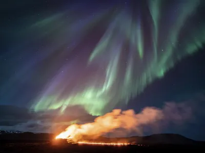 A view of the eruption area with the northern lights dancing in the sky near the town of Grindavik, Iceland, Tuesday April 16, 2024. The volcano in southwestern Iceland that erupted three times in December, January and February, sending lava towards a nearby community, keeps erupting. (AP Photo/Marco di Marco)