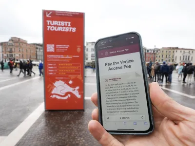 A tourist shows a QR code fee access outside the main train station in Venice, Italy, Thursday, April 25, 2024. The fragile lagoon city of Venice begins a pilot program Thursday to charge daytrippers a 5 euro entry fee that authorities hope will discourage tourists from arriving on peak days. The daytripper tax is being tested on 29 days through July, mostly weekends and holidays starting with Italy's Liberation Day holiday Thursday. Officials expect some 10,000 people will pay the fee to access the city on the first day, downloading a QR code to prove their payment, while another 70,000 will receive exceptions, for example, because they work in Venice or live in the Veneto region. (AP Photo/Luca Bruno)