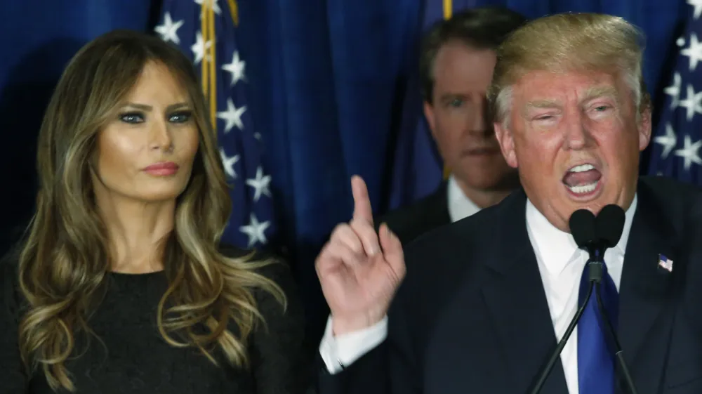Republican U.S. presidential candidate Donald Trump gestures during his victory speech as his wife Melania, looks on at his 2016 New Hampshire presidential primary night rally in Manchester, New Hampshire February 9, 2016. REUTERS/Jim Bourg - RTX269FU