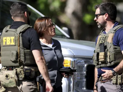 Members of FBI talk with each other at the scene of a shooting on Galway Drive in Charlotte, N.C., on Monday, April 29, 2024, Multiple law enforcement officers were shot while serving a warrant for a felon wanted for possessing a firearm. (Khadejeh Nikouyeh/The Charlotte Observer via AP)